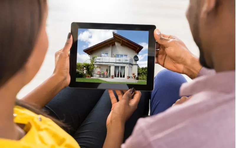 The best time to buy a house represented by a couple holding an ipad and looking at homes for sale