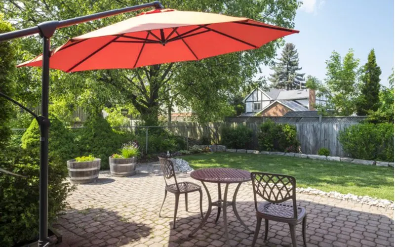 Red cantilever umbrella over a brick paver patio as a patio shade idea
