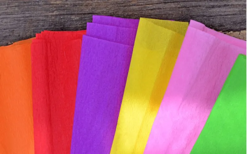 For a piece on how to frost glass, a bunch of colorful tissue paper sits on a wooden table