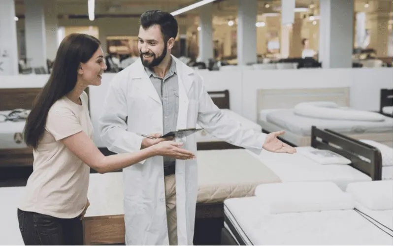 Woman walking through a mattress store with a doctor in a white coat