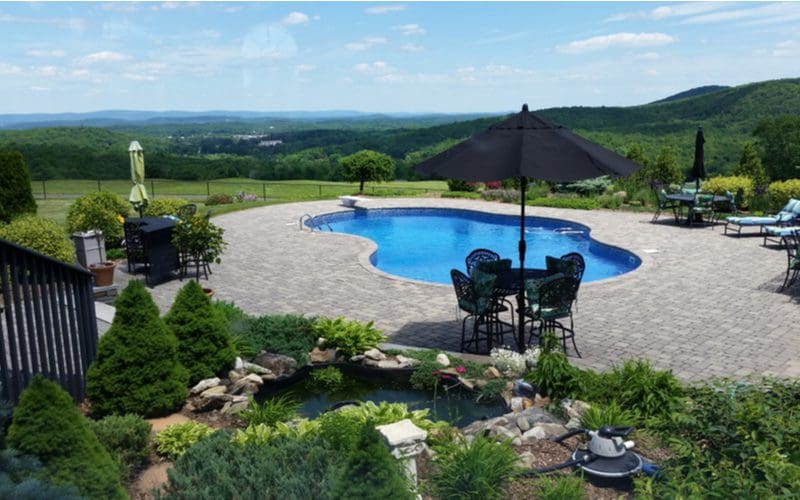 Paver patio idea making up a pool deck overlooking a lush green valley