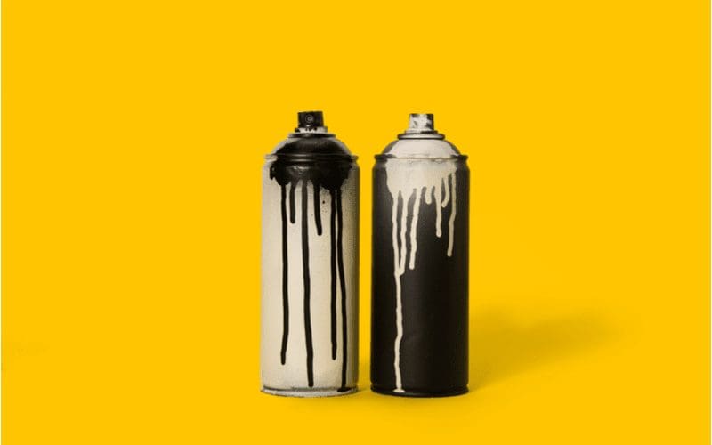 For a piece on how to frost glass, a can of black and off-white spray paint sit on an orange background