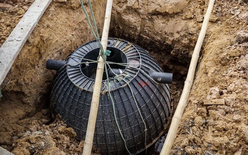 Installation of medium sized septic tank in the ground with excavator and ropes
