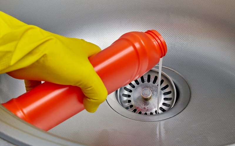Pouring chemical drain cleaner inside sink drain