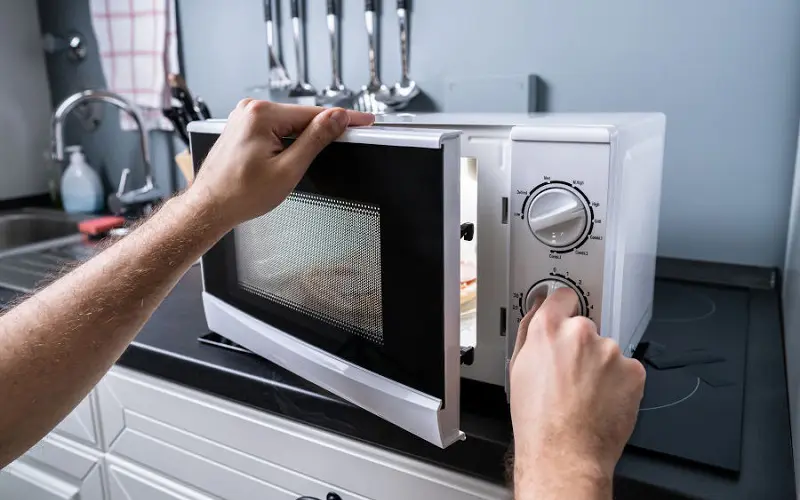 Man Preparing Food In Microwave Oven
