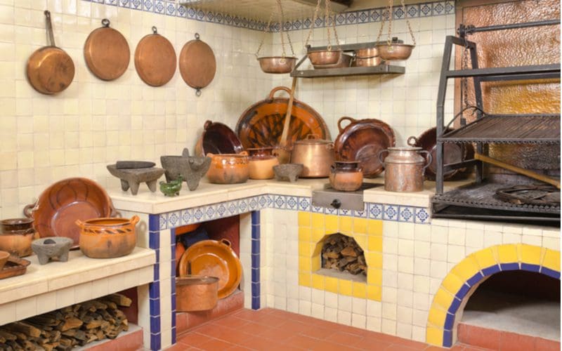 Rounded arches that make up most Mexican kitchens, as displayed in a kitchen with copper pots and pans and lots of small tiles on the counter and wall