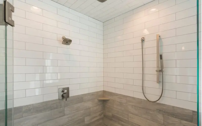 Two-toned tile shower idea with white subway tiled running horizontally on top and bigger grey wood-look subway tiles on the bottom