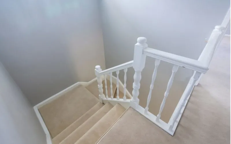 Simple white 3 inch stair trim idea with a white wavy railing across from it