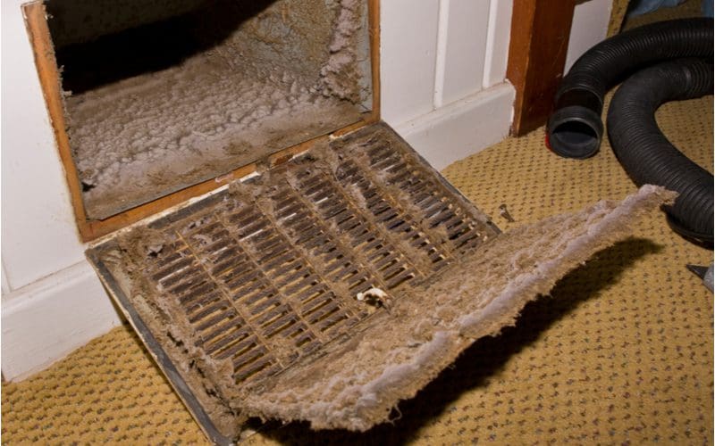 Extremely dirty air vent in a home with dust buildup to symbolize why you should regularly change your furnace filter