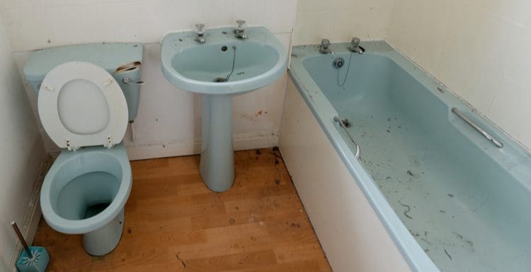 An old and dirty bathroom with an old tub that's a prime candidate for refinishing in blue porcelain