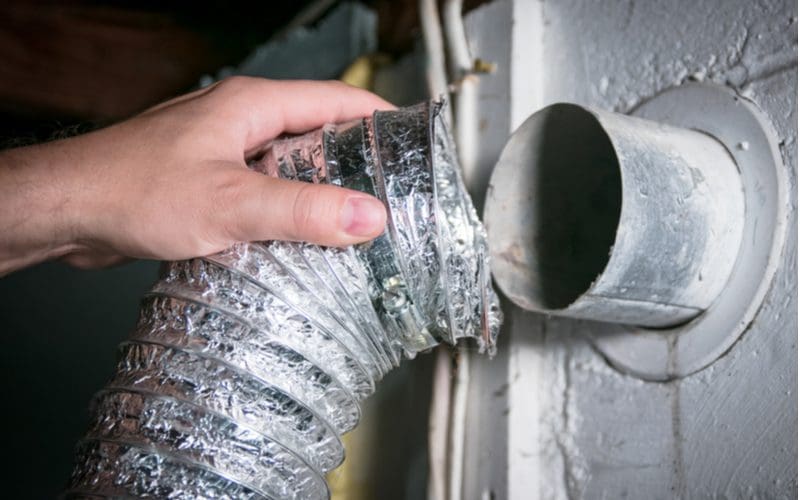 Guy reconnecting an aluminum tube after the dryer vent cleaning process was done