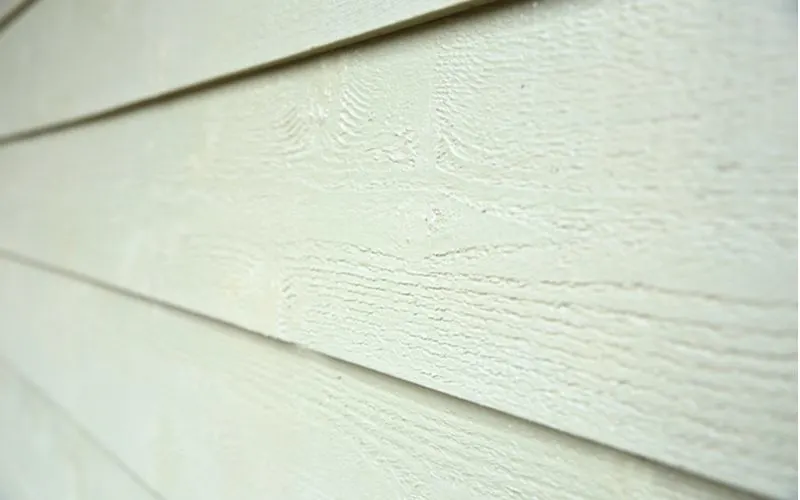 Close-up of fiber cement siding that runs laterally on a house painted very light green