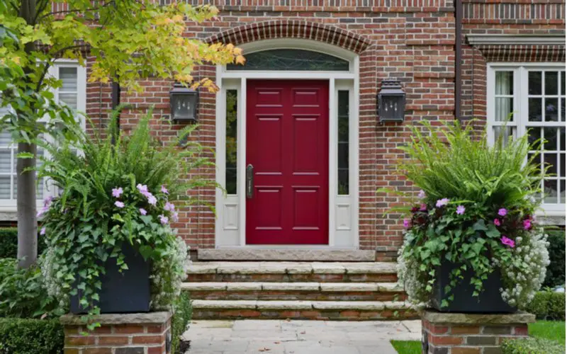 As one of the best front door color for red brick houses, a maroon door on a stately DC-styled brick home