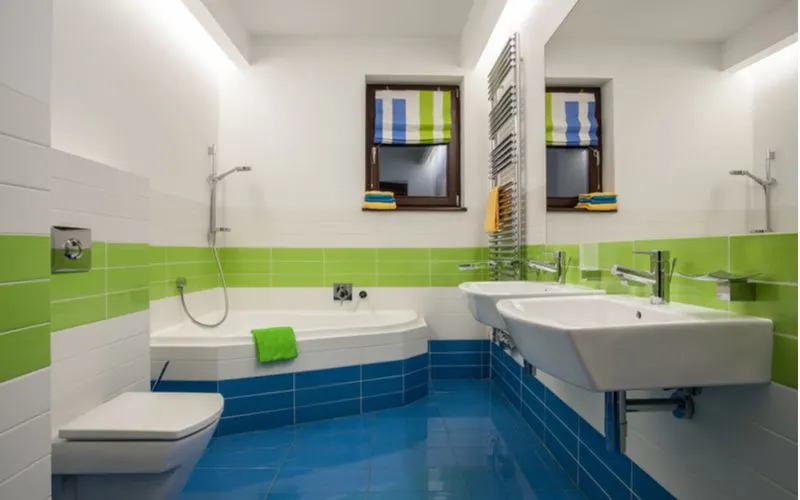 Bright and bold blue tile floored bathroom with white and green tile above it