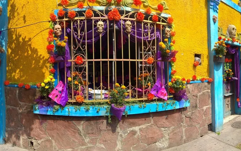 A Mexican kitchen as viewed from the outside in through metal grated with lots of skeletons adorning the walls