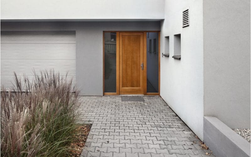 House entrance showing a modern stucco sided home with a simple but functional wooden door with two strips of glass on either side