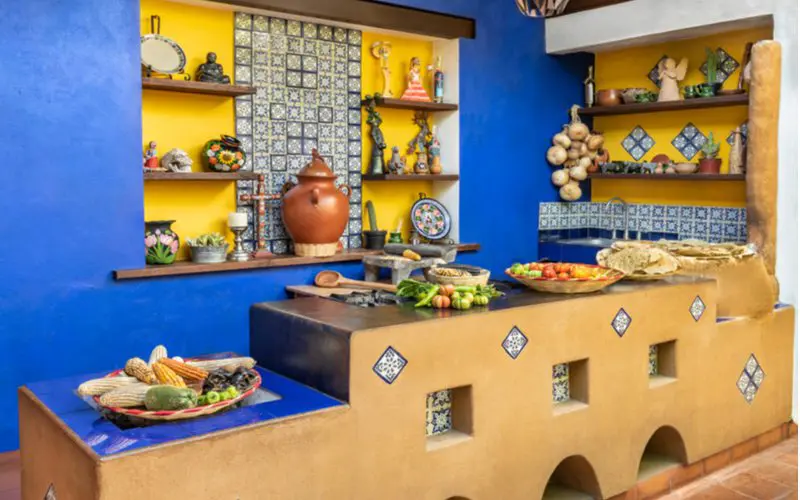 Open shelving, one of they key design traits of Mexican kitchens, in a blue and yellow kitchen