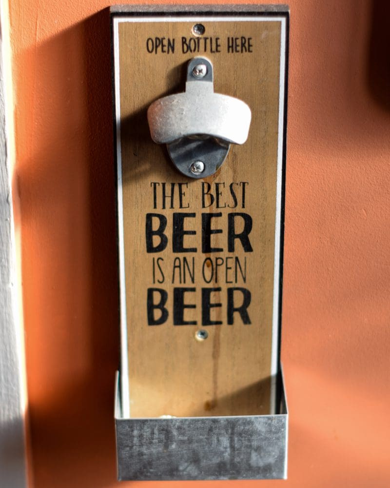Image of a bottle opener that says the best beer is an open beer for an idea for basement bar decor