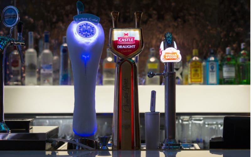 Illuminated keg handles sitting in front of a metal bar