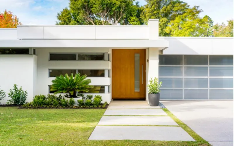 Modern white Australian house entrance idea with a porch next to a glass garage door