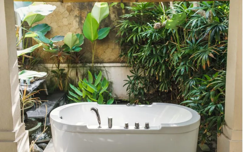Example of an outdoor bathroom to bring nature inside under a covered patio for a piece on bathroom inspiration ideas