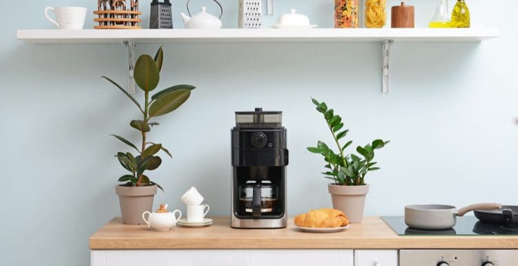 Featured image for a piece titled Coffee Station Ideas showing a drip coffee machine sitting on a wooden countertop