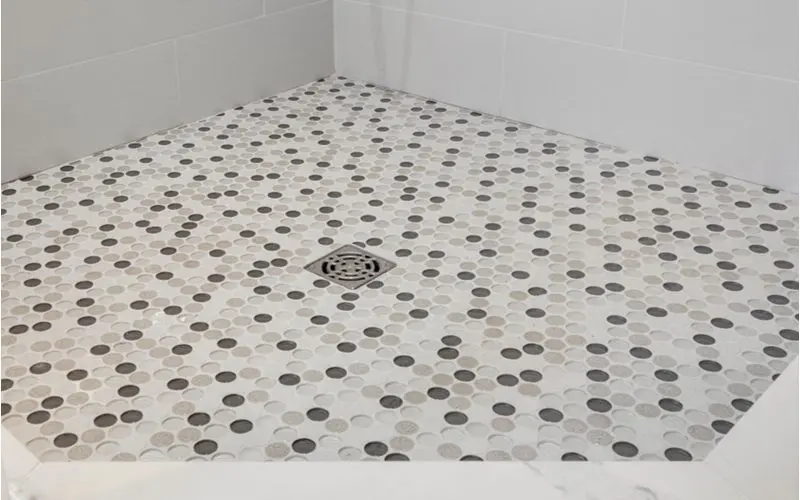 Round penny-sized glass tile shower idea with round tiles on the floor and white square tiles on the sides