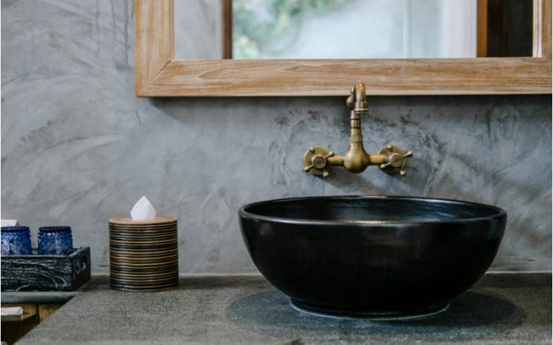 Grey tile bathroom idea with copper fixtures and a dark bronze sink bowl