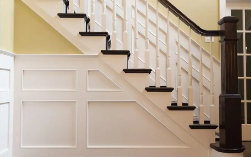 For a piece on wainscoting ideas, a number of wood panels painted white below the stairs 