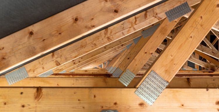 For a piece on trusses vs rafters, an interior shot of a home's roof structure with trusses with plates and a metal membrane attaching them