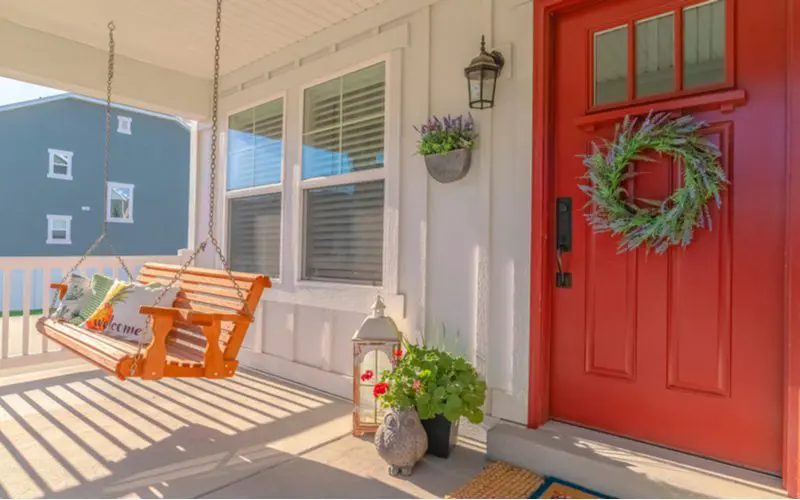 Front porch design idea with a red door and hanging porch swing
