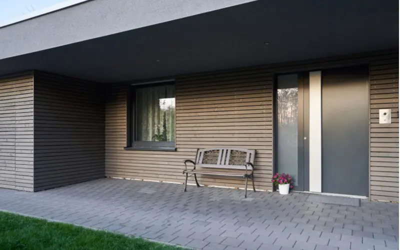 Brown and grey house idea with a big overhang with a patio made of grey square pavers