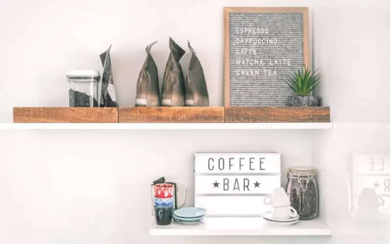 For a piece on coffee station ideas, floating shelves sit above such a station on which sit a number of trinkets related to coffee