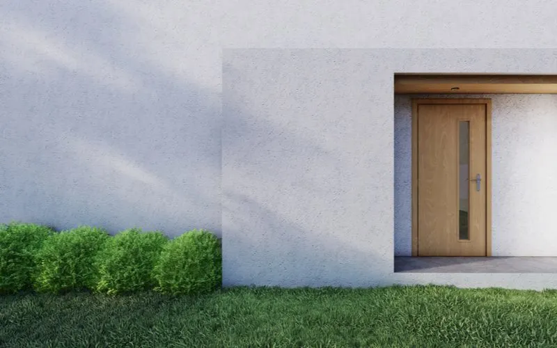 House entrance idea that blends a modern boxwood landscaping bed with a natural wood door