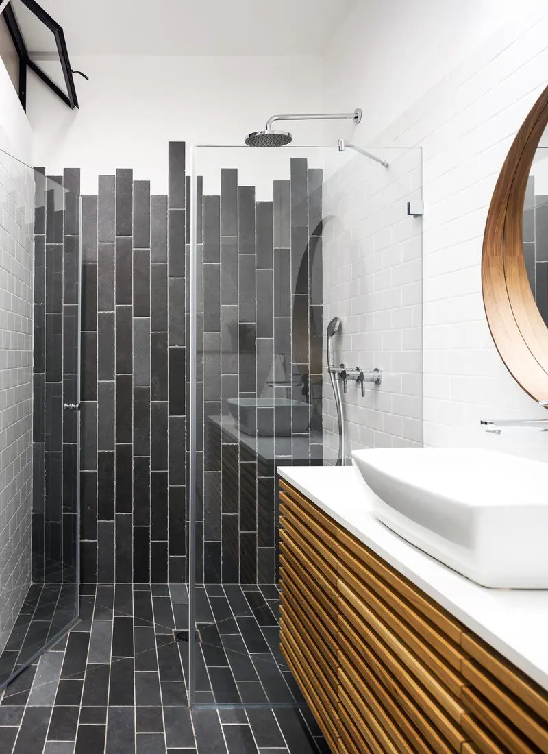 Bathroom with horizontal long tiles running vertically in an offset pattern that almost looks like paint dripping and a funky wood slatted vanity