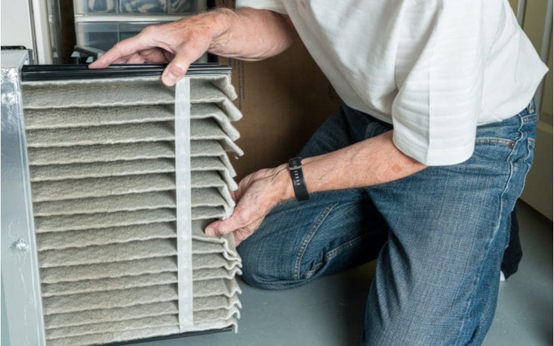Man sliding out a dirty furnace filter from his hvac unit