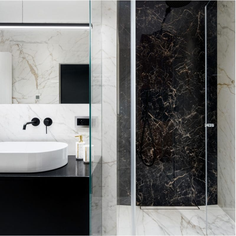 Striking black tile shower idea with an elegant black granite waterfall vanity and a stylish but modern square mirror