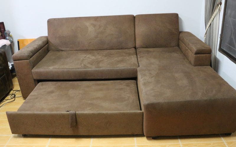 As an image for a piece on standard sofa dimensions, a brown faux suede couch pulled out into a bed