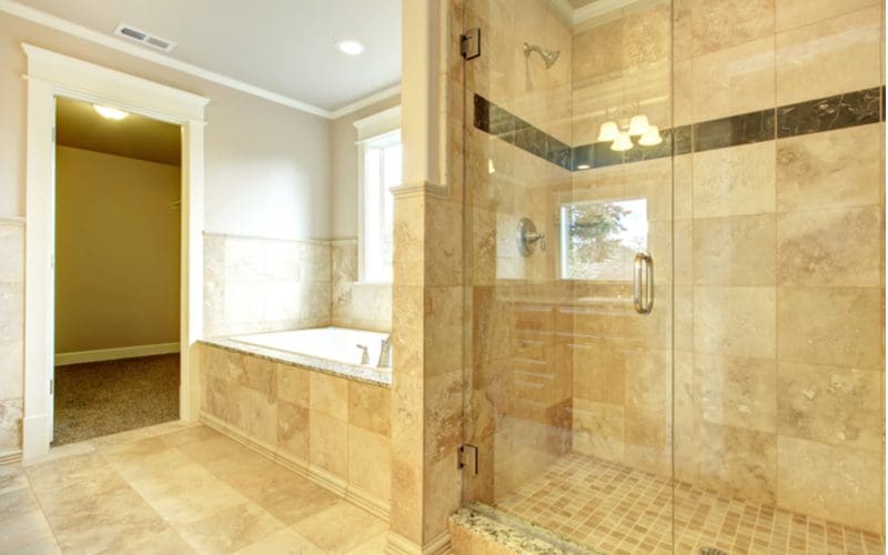 Bright white bathroom with overly beige tile on the shower, shower floor, tub deck, sides of the tub, and the floor