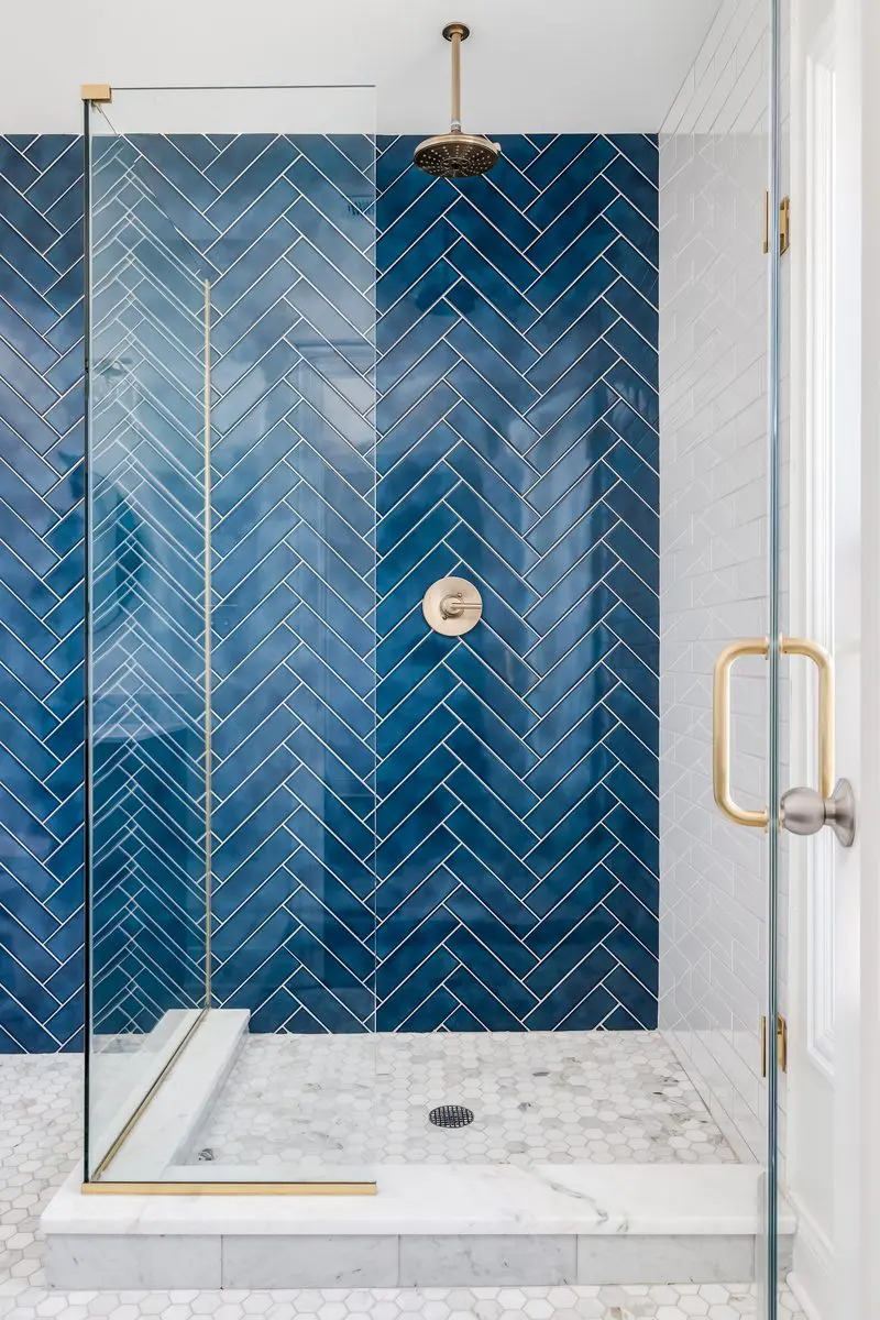 Blue walled tile shower idea in a herringbone pattern with glass walls on two sides with a rain showerhead above