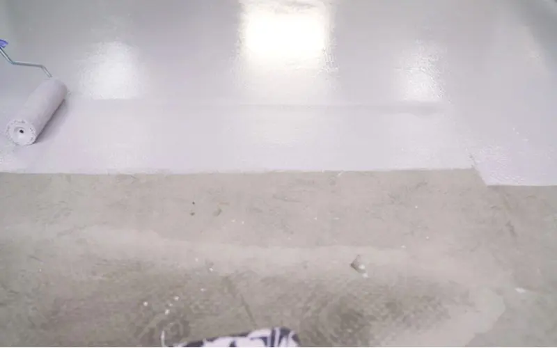 Roller painting a concrete basement floor grey
