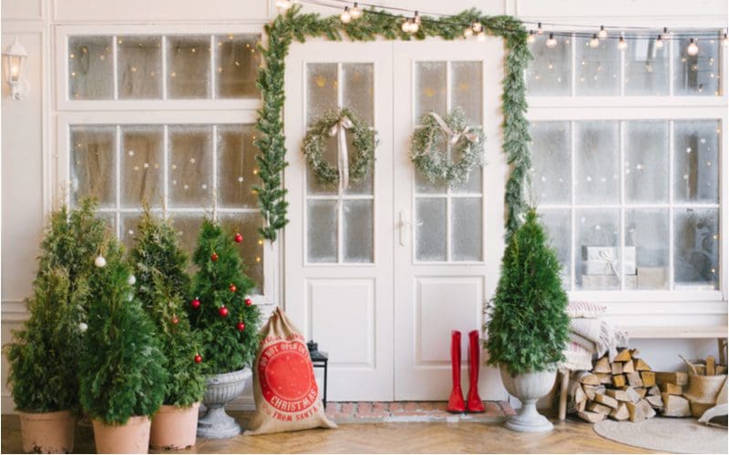 Seasonal decor house entrance idea with garland above the door next to boots and firewood