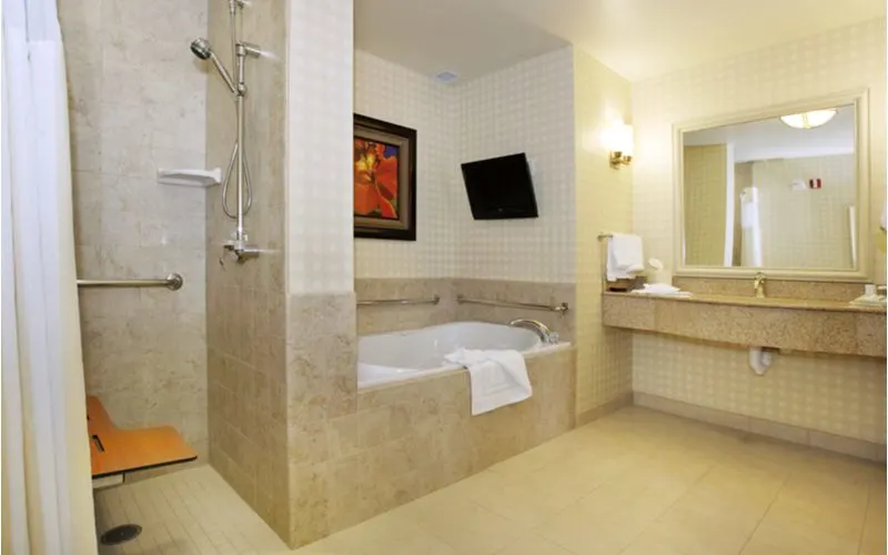 Ada-accessible walk in shower with a tv in the bathtub for a piece on walk in shower ideas