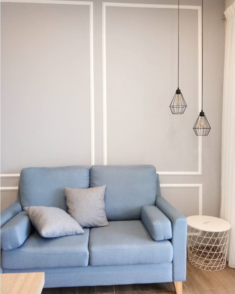 Grey wainscoting idea with white paint trimming the molding in back of a blue couch
