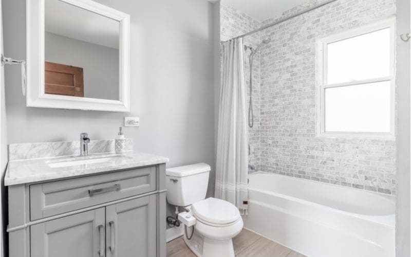 Minimalist grey tile bathroom with grey subway tile shower surround and grey wood-look floor tiles