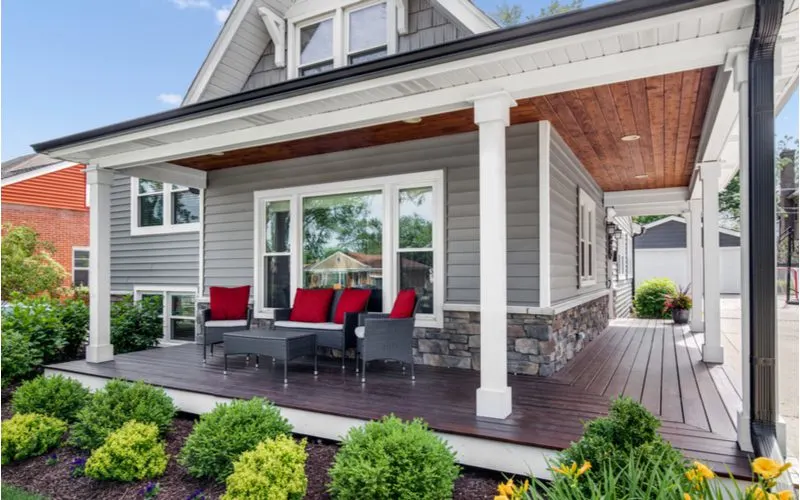 Image of a front porch idea with lots of boxwoods in front of a big wraparound porch