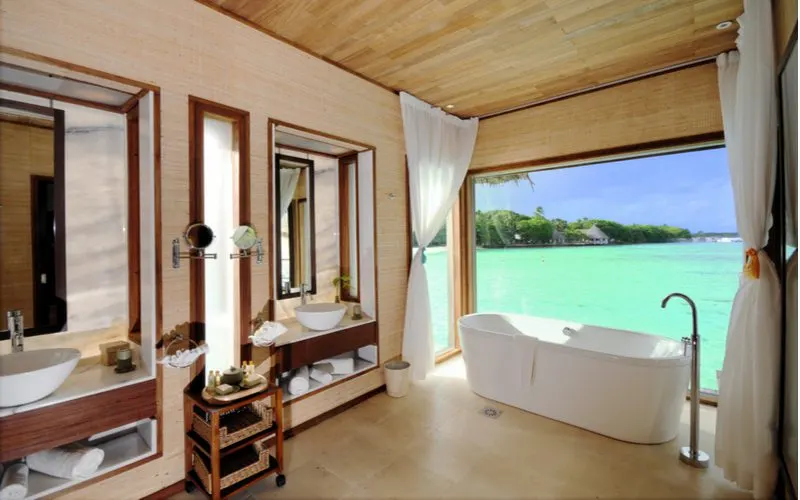 Beach resort bathroom idea with a wood-paneled bathroom overlooking light green ocean water