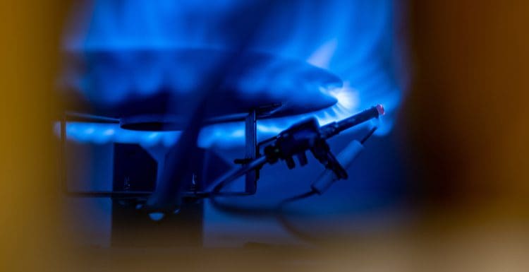 Featured image for a piece on how to light water heater pilot light showing a close-up of a burner inside a gas water heater