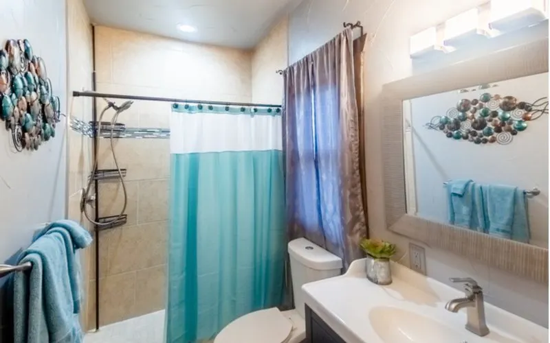 Bathroom idea titled Mermaid Motel with a teal curtain and tan surrounding tile