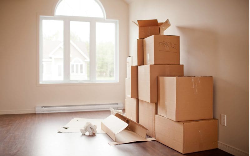 Couple packed up moving boxes and took our advice on the best time to sell a house, now their contents are packed up in a front room with arched windows overlooking a suburban neighborhood